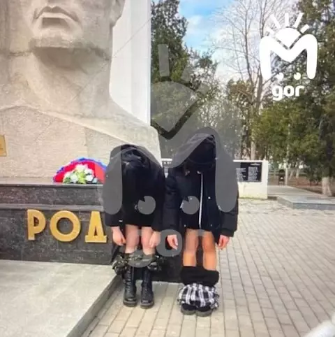 На провокационном снимки стоят две девушки, у которых не видно лиц из-за одежды. Но видны спущенные штаны, а позади них находится монумент.